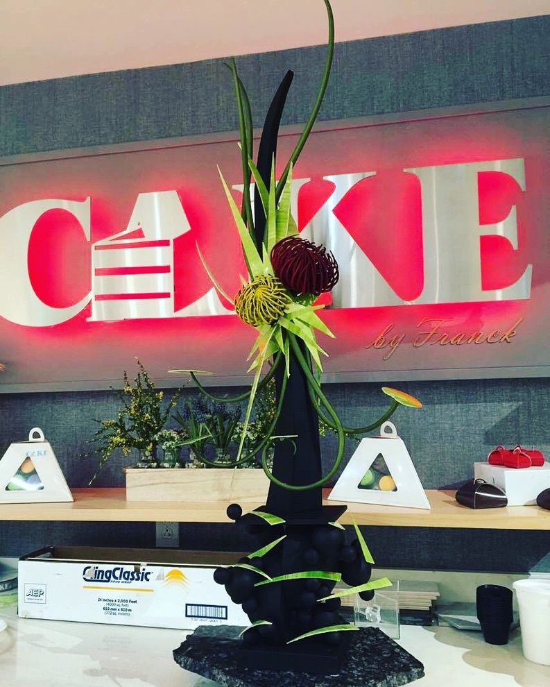 Pièce artistique en chocolat devant l’enseigne CAKE by Franck